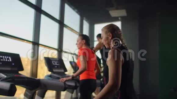 一个女人走到跑步机上打开它开始训练健身房健身室包括跑步机视频的预览图