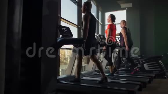 4名男女青年在跑步机上行走在训练前进行热身视频的预览图