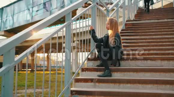 穿着皮夹克坐在楼梯上的女孩视频的预览图