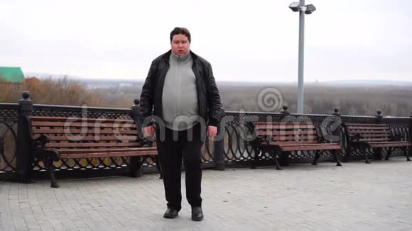 自信的胖子看着摄像机在城里散步视频的预览图