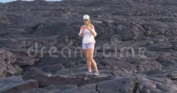 夏威夷Kilauea火山中的一位徒步女孩与流动的熔岩合影视频的预览图