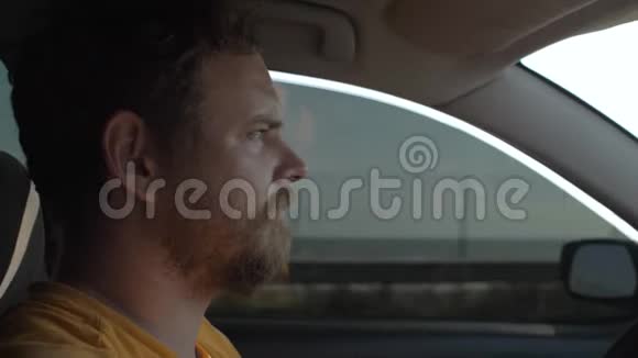 有胡子的人开着一辆车表情专注那家伙在大海的背景上开了一辆车4k4k录像慢慢慢慢视频的预览图