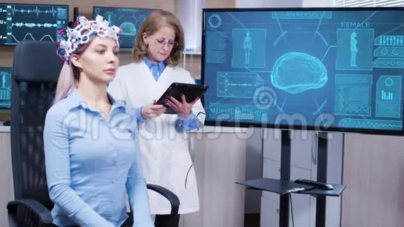 女性大脑活动的科学家用她的平板电脑在她的病人耳机上做最好的调整视频的预览图