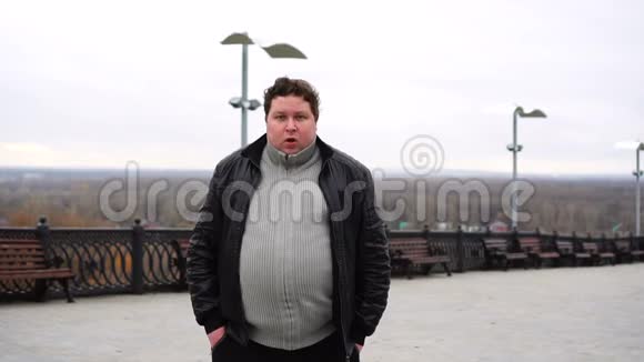 放大胖子的肖像看着相机在寒冷的秋天天气在户外咳嗽视频的预览图