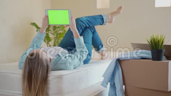 一个女人躺在床上用一个带有绿色屏幕的数字平板电脑视频的预览图
