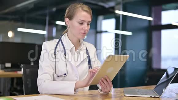 勤劳的年轻女医生在办公室里用平板电脑视频的预览图