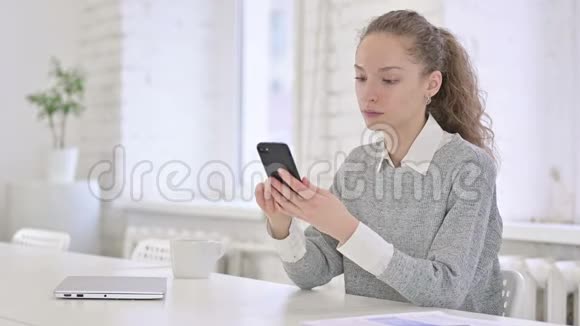 在现代办公环境中使用智能手机的年轻拉丁女性视频的预览图