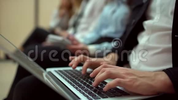 特写男子手在笔记本电脑上打字年轻学生坐在研讨会讲座和会议上视频的预览图