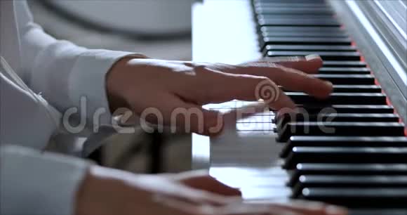 一名学生或专业钢琴家在一架漂亮的白色钢琴上演奏古典音乐钢琴家的手视频的预览图