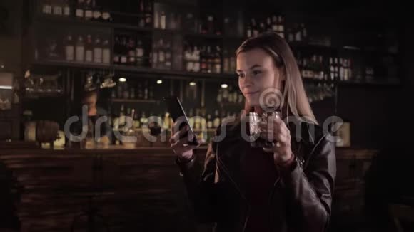 咖啡馆里的女孩年轻漂亮的女人在酒吧喝酒鸡尾酒酒保在酒吧里用手机上网视频的预览图