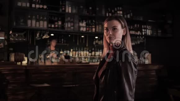 时尚酒吧里漂亮的年轻女子双臂交叉在胸前背景酒保正在准备鸡尾酒视频的预览图