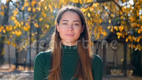 秋天黄树背景下一位年轻迷人的黑发女人的肖像视频的预览图