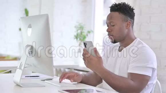 在现代办公室使用智能手机的专注休闲非洲男人视频的预览图