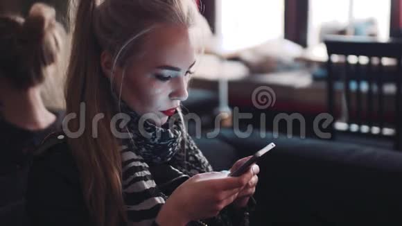 年轻女子用手机一边发电子邮件一边坐在咖啡馆A作为一个博主现代生活方式网上在线视频的预览图