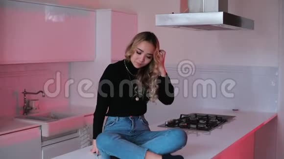 女孩坐在厨房的桌子上把头发放在手里视频的预览图