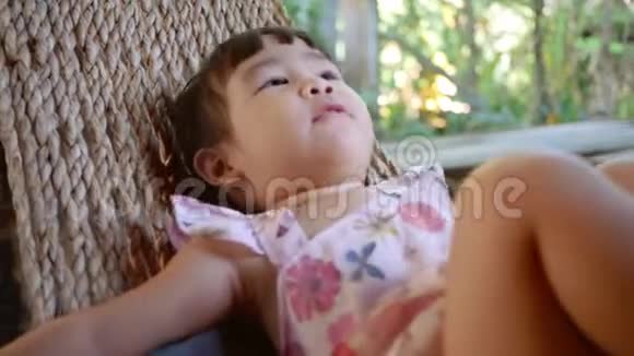 可爱的小女孩放松和躺在吊床户外花园视频的预览图