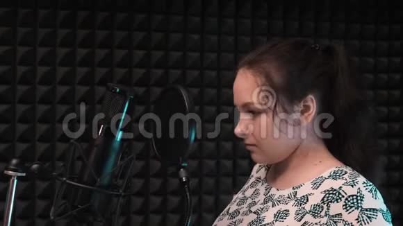 流行女艺术家戴上专业耳机一个蓝眼睛的漂亮女孩在专业录音室等待排练视频的预览图