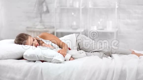 轻松的家庭妈妈和可爱的宝宝睡在白色的室内背景上视频的预览图