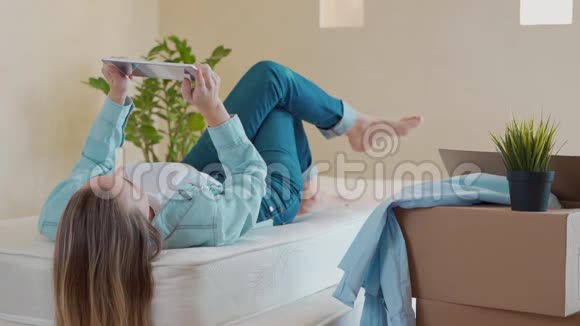 一个女人躺在床上用数码平板电脑视频的预览图