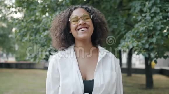 快乐的非裔美国女孩在城市公园户外大笑的慢动作视频的预览图