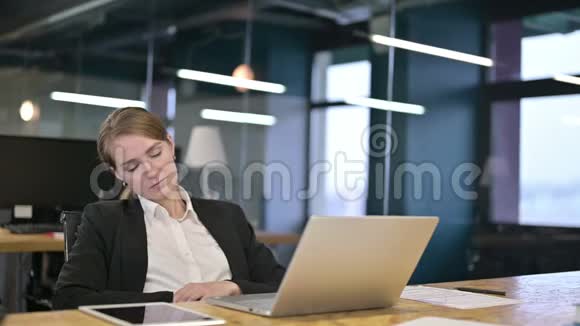睡眠不足的年轻女商人在现代办公室打盹视频的预览图