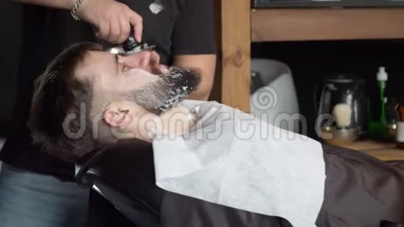 理发师在客户胡须上涂抹剃须泡沫视频的预览图