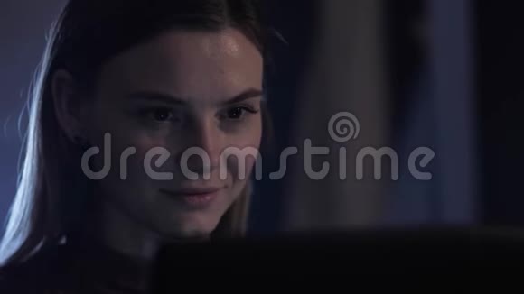 在笔记本电脑上工作晚上使用电脑的年轻女子的肖像脸上带着轻微的微笑印着文字和文字视频的预览图