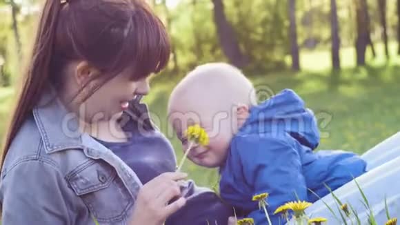 妈妈带着一个小孩子躺在公园的草地上家庭散步妈妈照顾视频的预览图