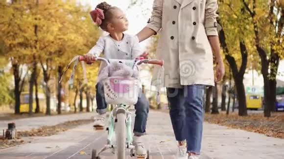 小女孩在妈妈的支持下学会骑自行车视频的预览图