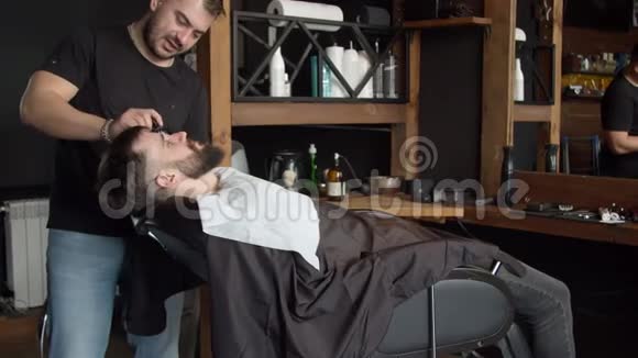 理发师在客户胡须上涂抹剃须泡沫视频的预览图