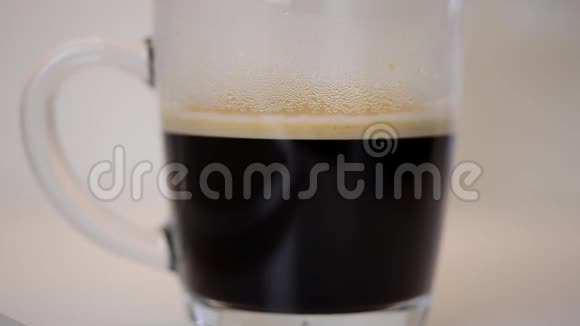 牛奶正在倒入一杯清澈的黑色新鲜热浓咖啡咖啡具有慢动作效果视频的预览图