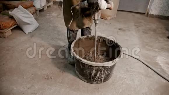 混凝土工业用手搅拌机将混凝土从水泥水和玻璃碎片中搅拌出来视频的预览图