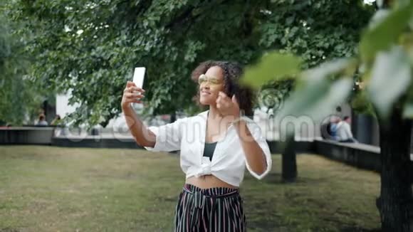 城市公园里的混血女士手持智能手机拍照视频的预览图
