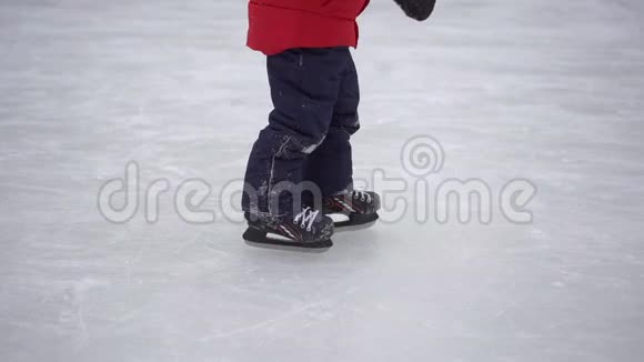 年轻的妈妈和一个小男孩在溜冰场上小男孩学会滑冰冬季活动概念视频的预览图