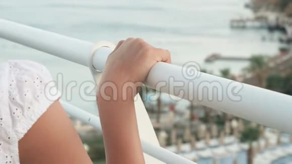 女性手滑在白色扶手上夏季阳台海景把少年女孩的手放在户外栏杆上视频的预览图