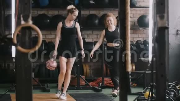 两个年轻漂亮的白人运动女性走在健身房带着水壶的重量随便说慢动作视频的预览图