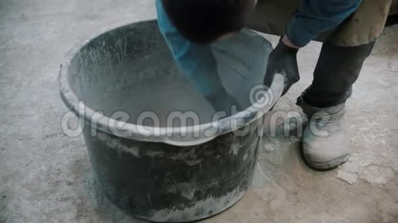 混凝土行业手套工人从水泥残留物中清洗桶视频的预览图