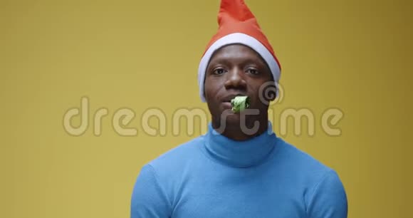 在圣诞老人帽子里吹派对喇叭的人视频的预览图