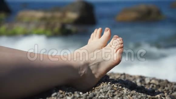 女腿背景沙滩上的鹅卵石海休息和放松慢动作度假视频的预览图
