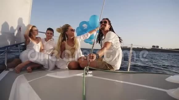 四个朋友在游艇上放松巡航同时躺在船头他们享受这一刻一个女孩视频的预览图