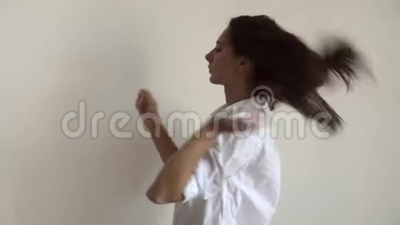 室内肖像的年轻女子收集头发马尾辫穿白色衬衫早晨简单的例行公事视频的预览图