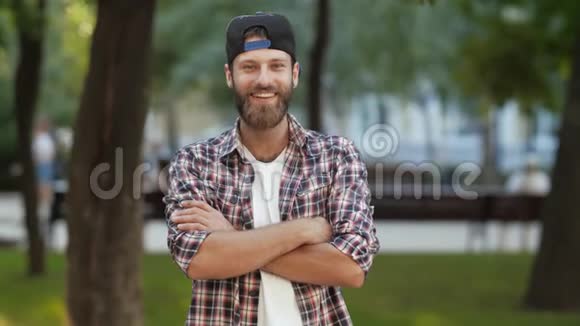 一个穿着衬衫戴着双臂帽子的微笑男人视频的预览图