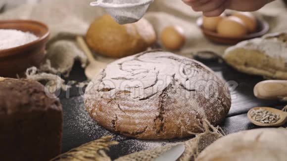 在面包店里一个面包师在烤完新鲜面包后把糖粉粉洒在面包粉糕点上视频的预览图