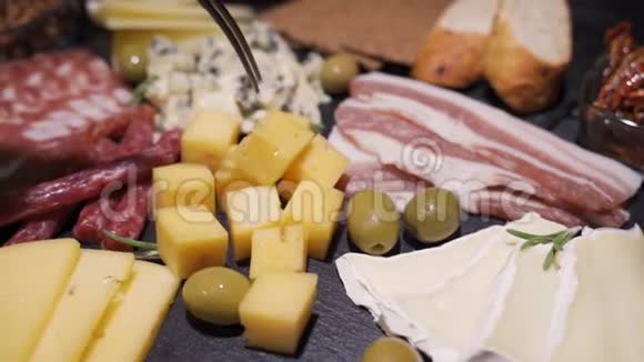 女性手从橄榄板上拿奶酪的慢动作幻灯片视频的预览图