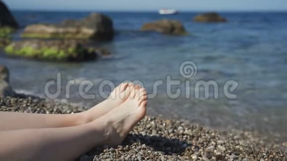 阳光明媚的一天女孩的腿躺在海滩上关闭慢动作视频的预览图