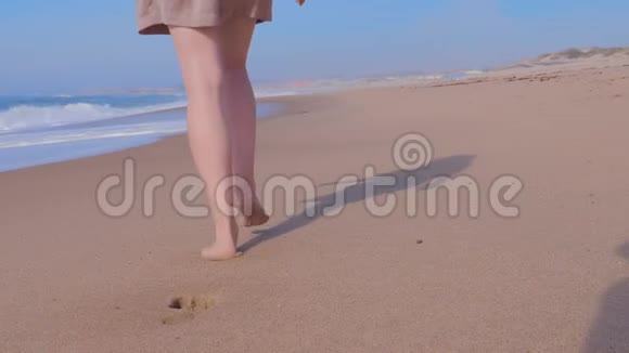 女人在潮湿的沙滩上行走海浪视频的预览图