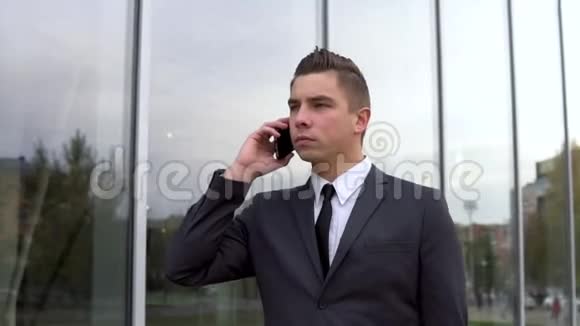 一个穿西装的年轻商人走着打电话严肃的男人特写背景镜业务中心视频的预览图