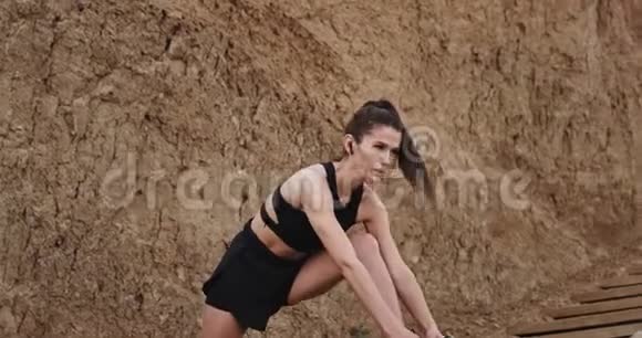 美丽运动的女士在海边的木台阶上锻炼身体听音乐视频的预览图