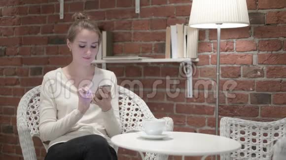 年轻女子喝咖啡对智能手机的故障做出反应视频的预览图