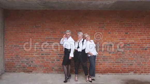 三个白种人金发碧眼的女商人站在砖墙上视频的预览图